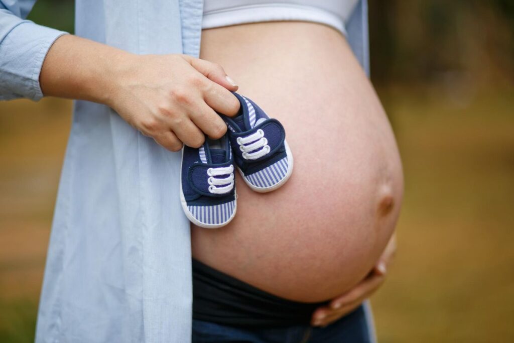 Mujer embarazada con zapatillas azules para el bebé