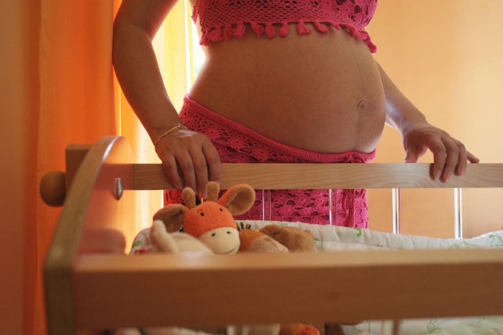 Embarazada apoyada en una cuna